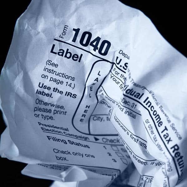 A crumpled U.S. IRS Form 1040 hints at the public's appetite for Tax Reform against a dark background.