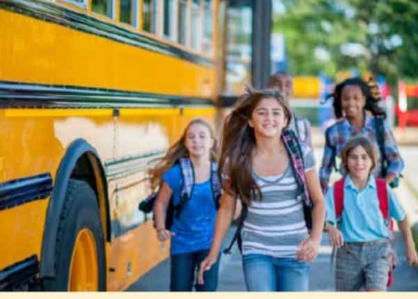 Four children with backpacks walk from a yellow school bus, highlighting Louisiana education policies on a sunny day.