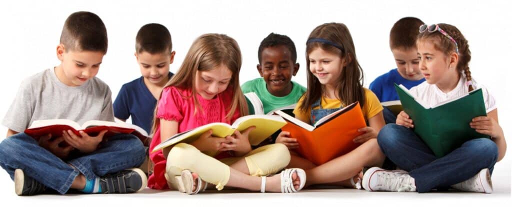 Six children sit in a row on the floor, smiling and reading colorful books—showcasing joyful reading in Louisiana teacher preparation programs.