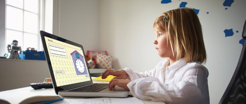 A young girl sits at a desk using a laptop for an education activity, bridging the digital divide with clocks and time exercises.