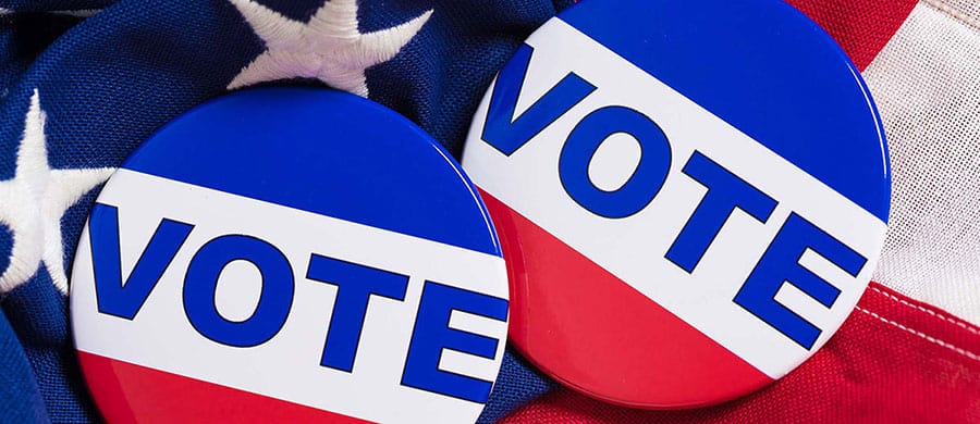 Two round "VOTE" buttons with a red, white, and blue design highlight the importance of Election Day on an American flag background.