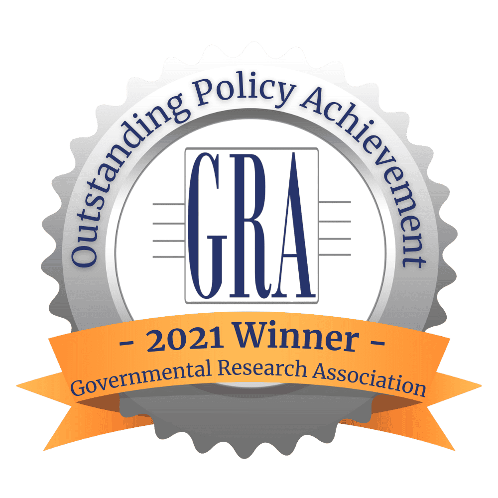 Silver seal badge reading "Outstanding Policy Achievement," "GRA," and "National Award — 2021 Winner, Governmental Research Association" on ribbon.