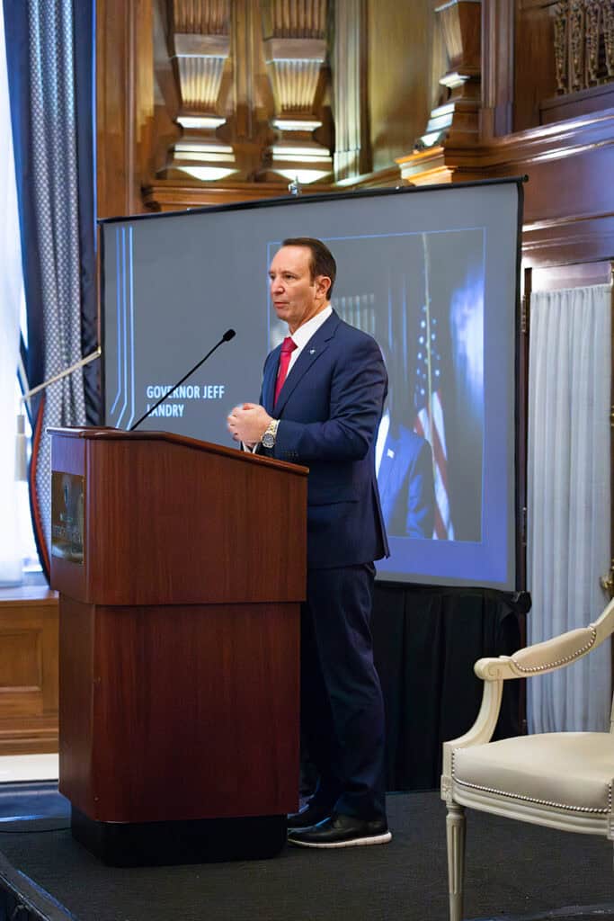 A man in a suit speaks at a podium on the lawmaking process, with