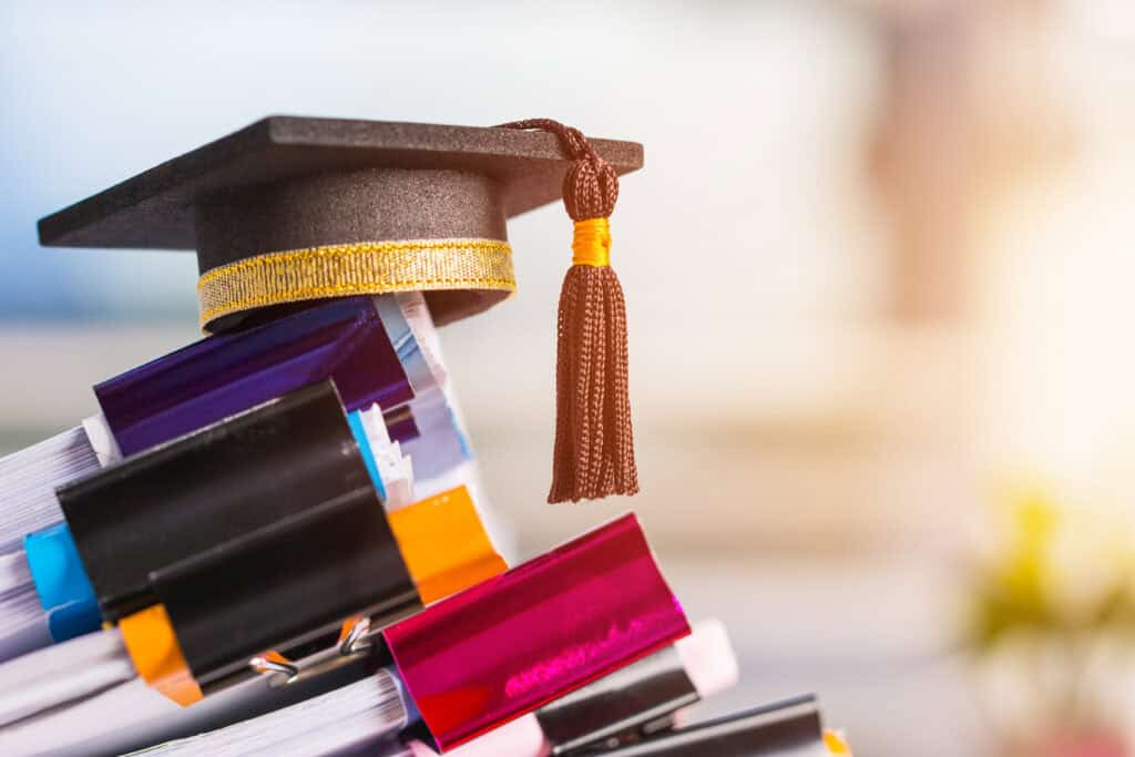 A graduation cap tops colorful, binder-clipped documents, symbolizing academic achievement and Leadership Louisiana excellence.